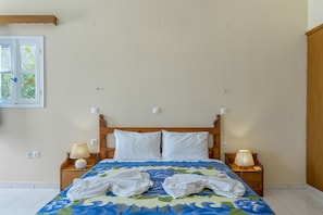 Um quarto com uma cama, duas mesas de cabeceira, uma janela e uma porta.