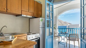 A kitchen with wooden cabinets, a stove, and a refrigerator. There is a balcony with a table and chairs.