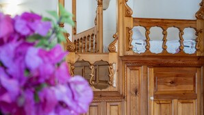 A wooden staircase with ornate railings and a floral arrangement in the foreground. - Apartment 'No 2' with Sea View, Wi-Fi and Air Conditioning (Karpathos)
