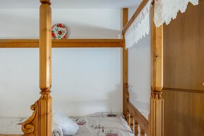 A wooden four-poster bed with a white bedspread and a decorative plate on the wall.