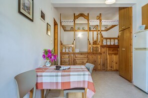 A kitchen with wooden cabinets, a table with a checkered tablecloth, and a vase with flowers.