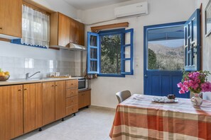 A kitchen with wooden cabinets, a sink, and a window with blue shutters.