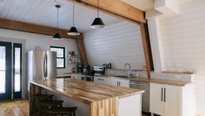 A modern kitchen with a wooden island, white cabinetry, and pendant lighting.