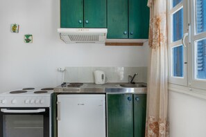 Een keuken met een fornuis, een koelkast en groene kasten.