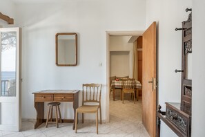 Quarto com escrivaninha, cadeira, espelho e área de refeições com mesa e cadeiras.