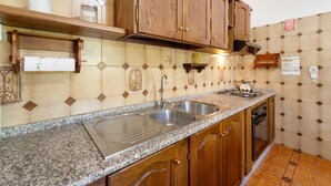 Una cocina con encimeras de granito, armarios de madera, un lavaplatos de acero inoxidable y una estufa.
