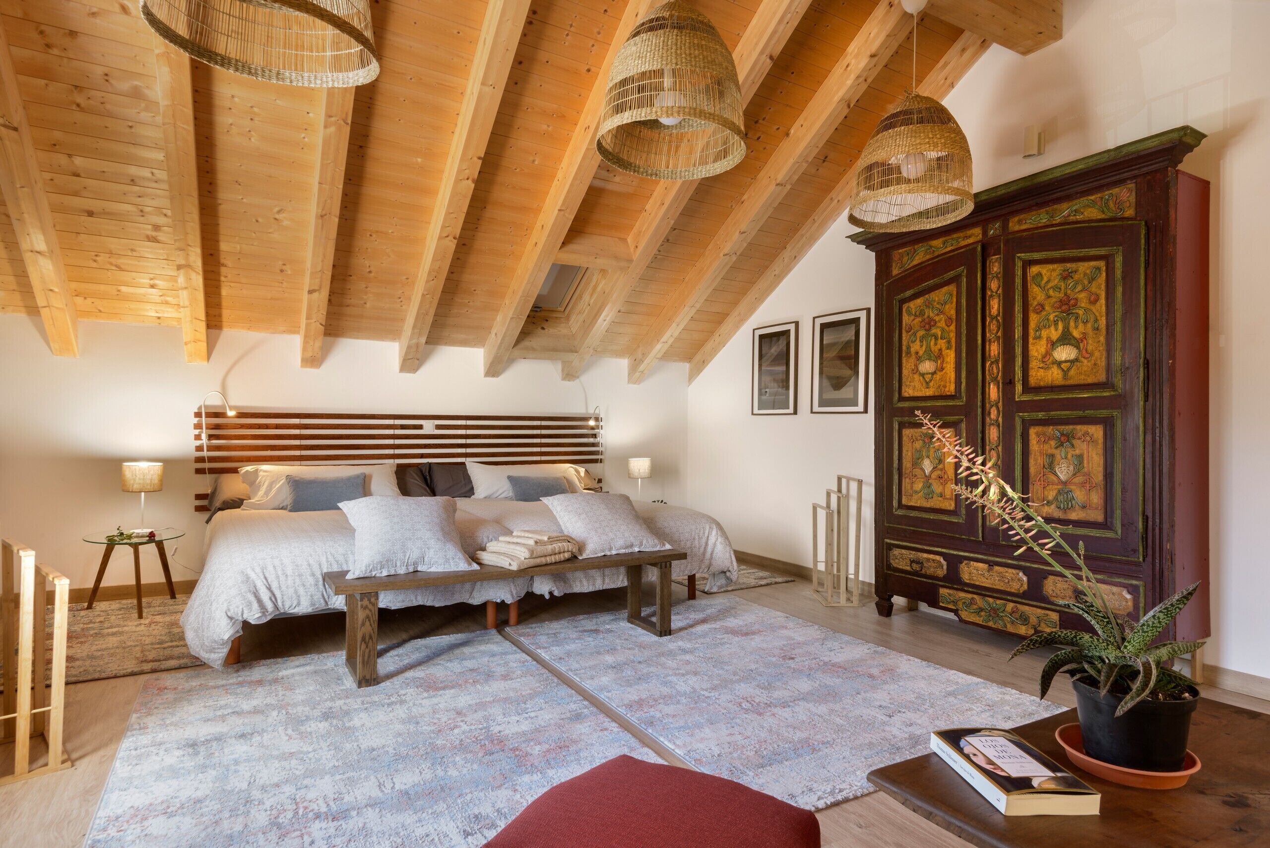 Een slaapkamer met een bed, nachtkastjes, een grote kast en een hanglamp.