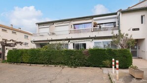 A two-story residential building with a balcony, a sign reading "LE TOUCAN," and a well-maintained hedge in front. - AS25806-P2 duplex cabin with terrace and parking (LE GRAU DU ROI)