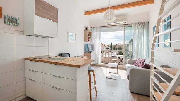 A modern kitchen with a wooden countertop, white cabinets, and a dining area with a table and chairs. - AS25806-P2 duplex cabin with terrace and parking (LE GRAU DU ROI)