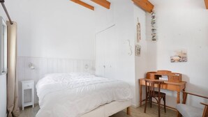 A bedroom with a bed, a small bedside table, a wooden desk with a chair, and a wall-mounted shelf. - AS25806-P2 duplex cabin with terrace and parking (LE GRAU DU ROI)
