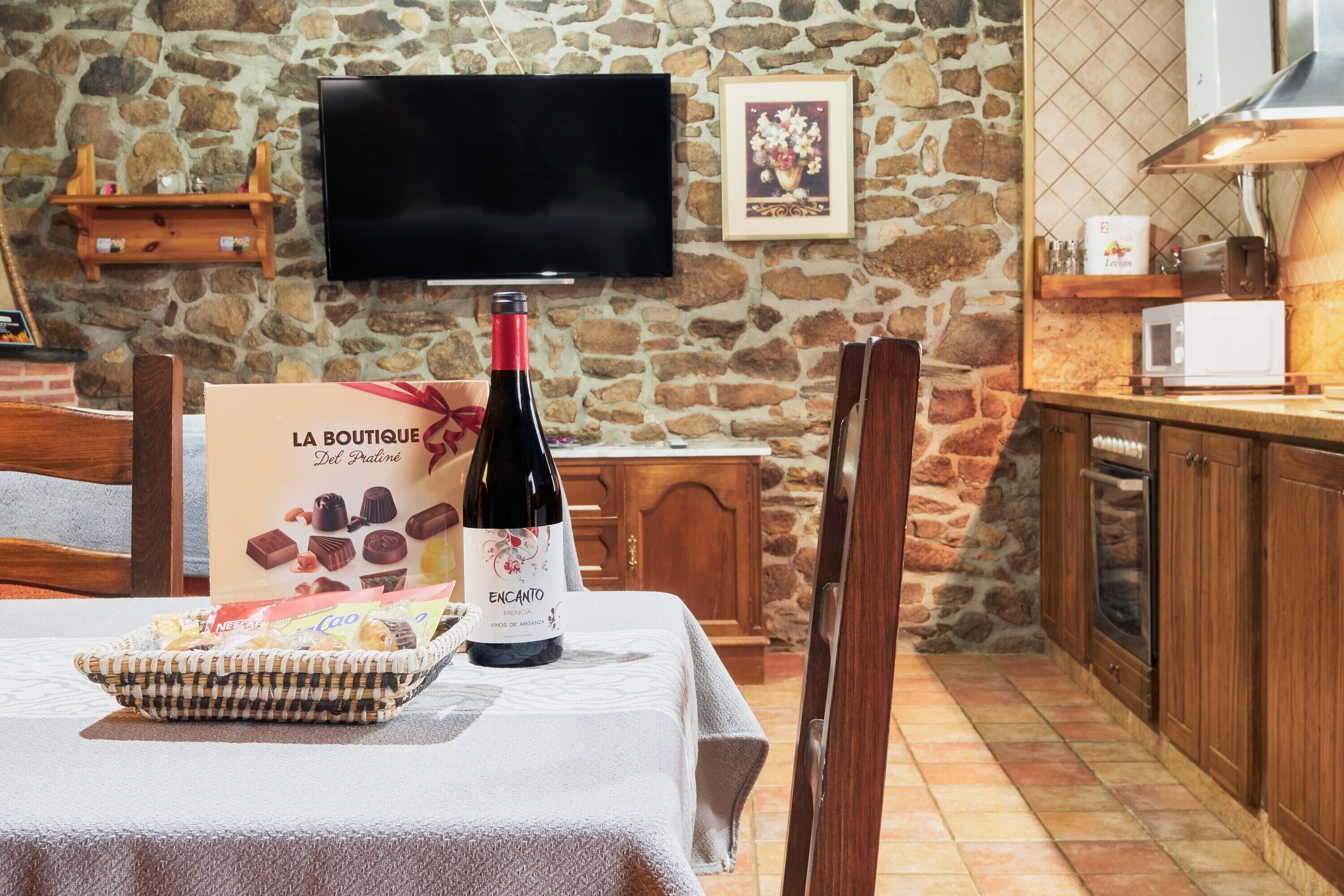 A stone wall, a television, a wine bottle, a sign, and a microwave in a kitchen area.