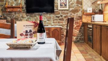 A stone wall, a television, a wine bottle, a sign, and a microwave in a kitchen area.