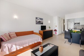Une chambre moderne équipée d’un lit, d’une télévision, d’un petit coin repas et d’une cuisine.