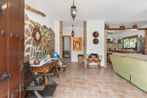 Un amplio espacio habitable con una mesa de comedor, sillas, un sofá y una cocina al fondo.