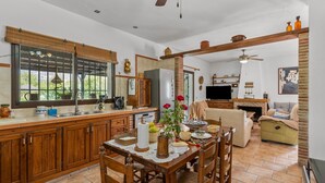 A spacious kitchen with wooden cabinets, a dining table with chairs, a TV, and a fireplace. - Country House 'Villa Pinale Álora' with Mountain View, Wi-Fi and Air Conditioning (Álora)