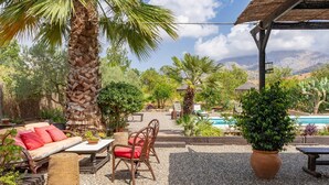 A patio with a sofa, chairs, a table, and a large potted plant. - Country House 'Villa Pinale Álora' with Mountain View, Wi-Fi and Air Conditioning (Álora)