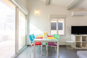 A bright room with a white table, colorful chairs, a TV, and a window.