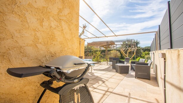 Une terrasse avec un barbecue, du mobilier d’extérieur et une pergola.