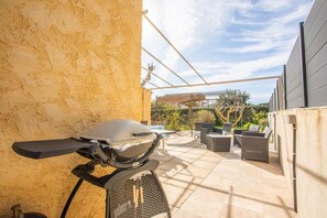 A patio with a grill, outdoor furniture, and a pergola.