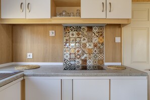 A kitchen with a patterned backsplash, wooden cabinets, and a granite countertop.