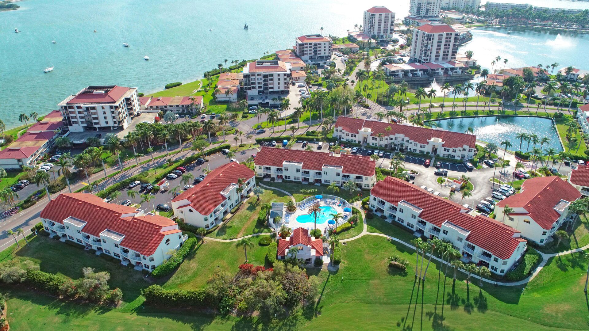 Ein Resort mit mehreren Gebäuden, einem zentralen Poolbereich und einer Marina mit Booten.
