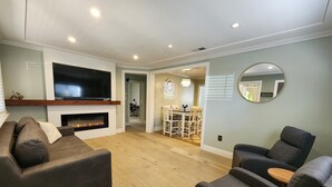 Un salon moderne doté d’un téléviseur à écran plat, d’une cheminée et de sièges confortables.