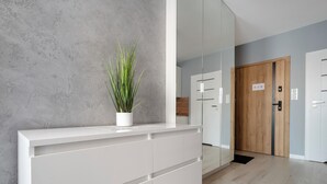 Een modern interieur met een witte console tafel, een kamerplant en een houten deur.