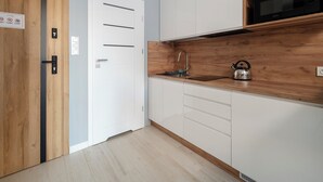 Een moderne keuken met houten kastjes, een ingebouwde magnetron en een waterkoker op het aanrecht.