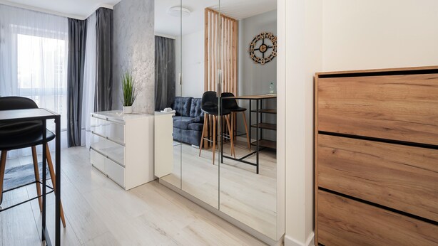 Een moderne woonkamer met een bank, een eettafel en een spiegelkast.