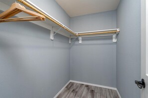 Een hoekkamer met een houten kledingrek, een witte deur en een houten vloer.