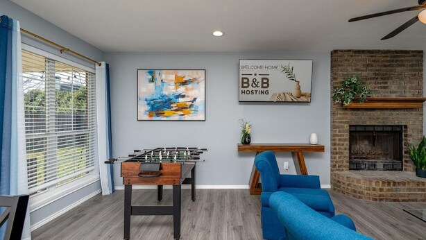 Ein Wohnzimmer mit einem Tischfußballtisch, einem blauen Sofa, einem Kamin und einem Schild mit der Aufschrift 'Welcome Home'.