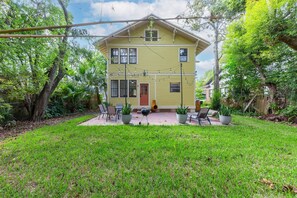 A two-story house with a front porch, surrounded by a well-maintained lawn and trees. - Gathering House at Riverside (Jacksonville)