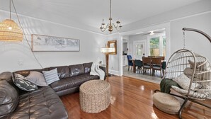 Un salon moderne avec un canapé en cuir, un fauteuil suspendu et un coin repas comprenant une table et des chaises.