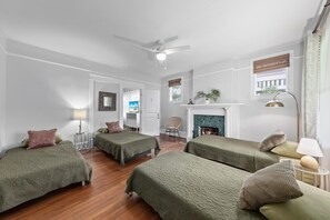 A room with two beds, a fireplace, a ceiling fan, and a desk with a chair. - Gathering House at Riverside (Jacksonville)