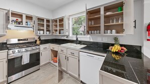 Une cuisine moderne avec des meubles blancs, une cuisinière en acier inoxydable et un plan de travail noir.