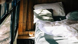 A cozy bed with a pillow and a cup of coffee on a wooden platform. - Bus & Hot Tub Secluded Eco Forest Retreat (Dysart)