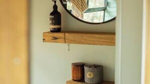 A room with a wooden ceiling, a round mirror, and two wooden shelves with items on them. - Bus & Hot Tub Secluded Eco Forest Retreat (Dysart)
