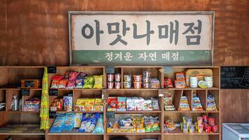 A snack shop with a variety of packaged snacks and condiments displayed on wooden shelves.