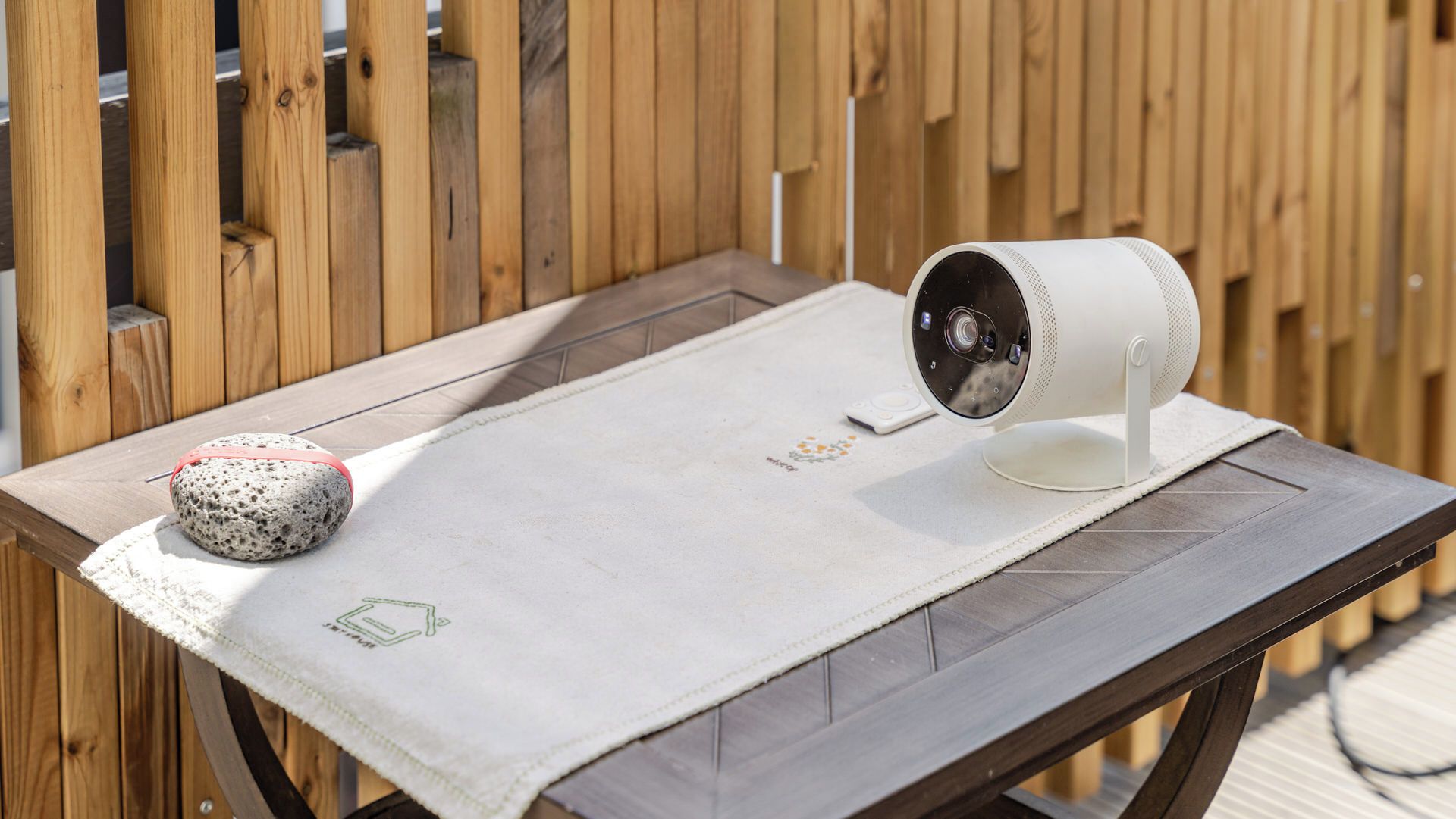 A table with a white cloth, a stone object, and a white device on it.