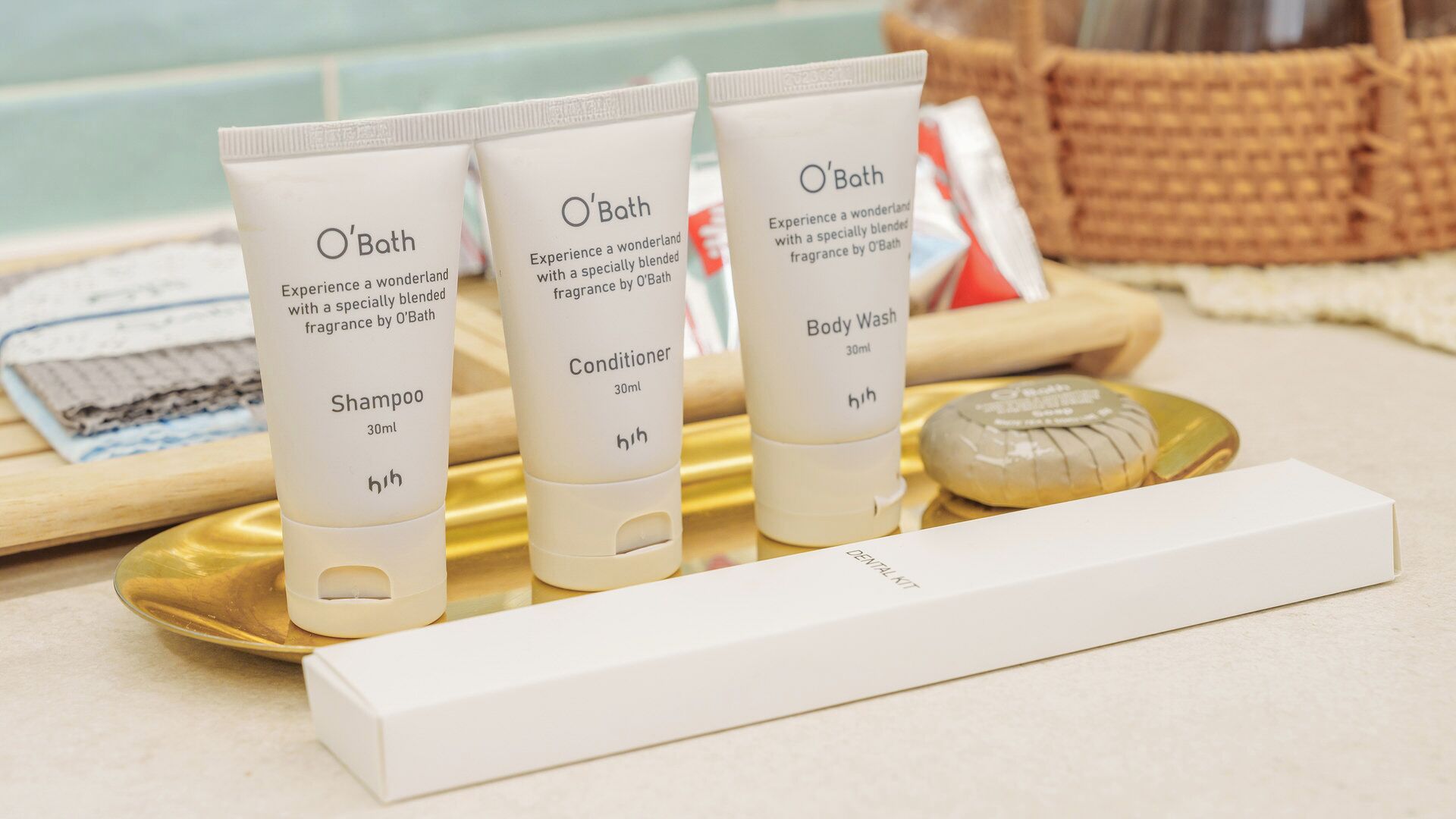 Three O'Bath products: shampoo, conditioner, and body wash, on a tray with a soap bar and a box.