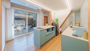 Une cuisine moderne dotée d’un îlot central, un coin repas avec une porte vitrée donnant sur un balcon, et un escalier menant à l’étage supérieur.