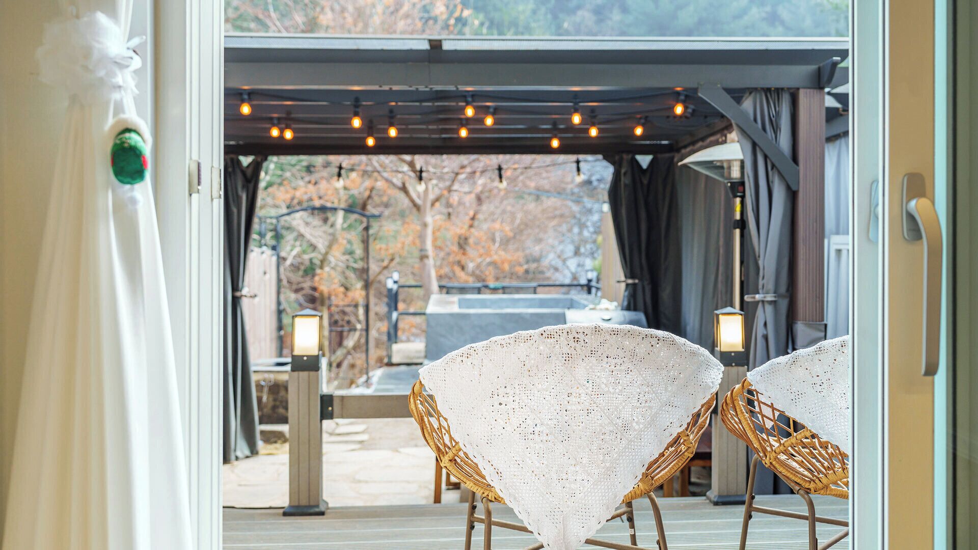 An outdoor seating area with wicker chairs and a pergola with string lights.