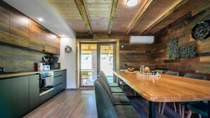 A modern kitchen with wooden cabinetry and a built-in oven. There is a dining area with a wooden table and chairs. - Stunning home in Prvan Selo with sauna (Prvan Selo)