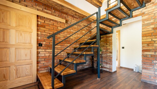 A wooden staircase with metal railings against a brick wall, leading to a door. - Stunning home in Prvan Selo with sauna (Prvan Selo)