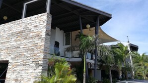 Un edificio con fachada de piedra, un letrero que dice "Punto 115 Centro Gastronomico" y un área exterior cubierta con palmeras.