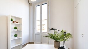 A room with a white desk, a potted plant, a lamp, and a bookshelf with small plants. - GuestHost - Casa Calise - Elegant 1920s Villa w/ Garage (Siena)