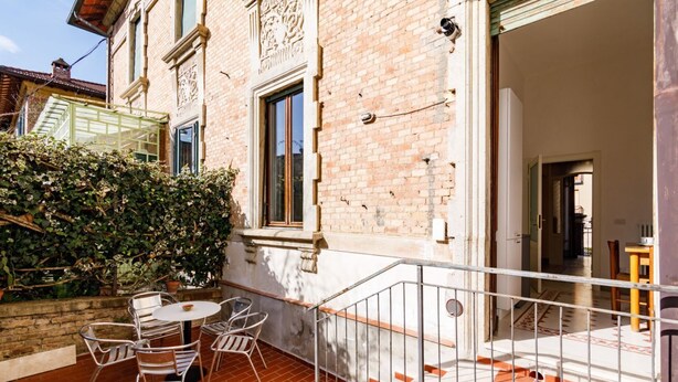 A patio with a table and chairs, a brick wall, and a metal railing. - GuestHost - Casa Calise - Elegant 1920s Villa w/ Garage (Siena)