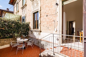 A patio with a table and chairs, a brick wall, and a metal railing.