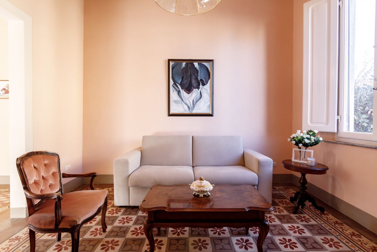 A living room with a sofa, armchair, coffee table, and a framed artwork on the wall.