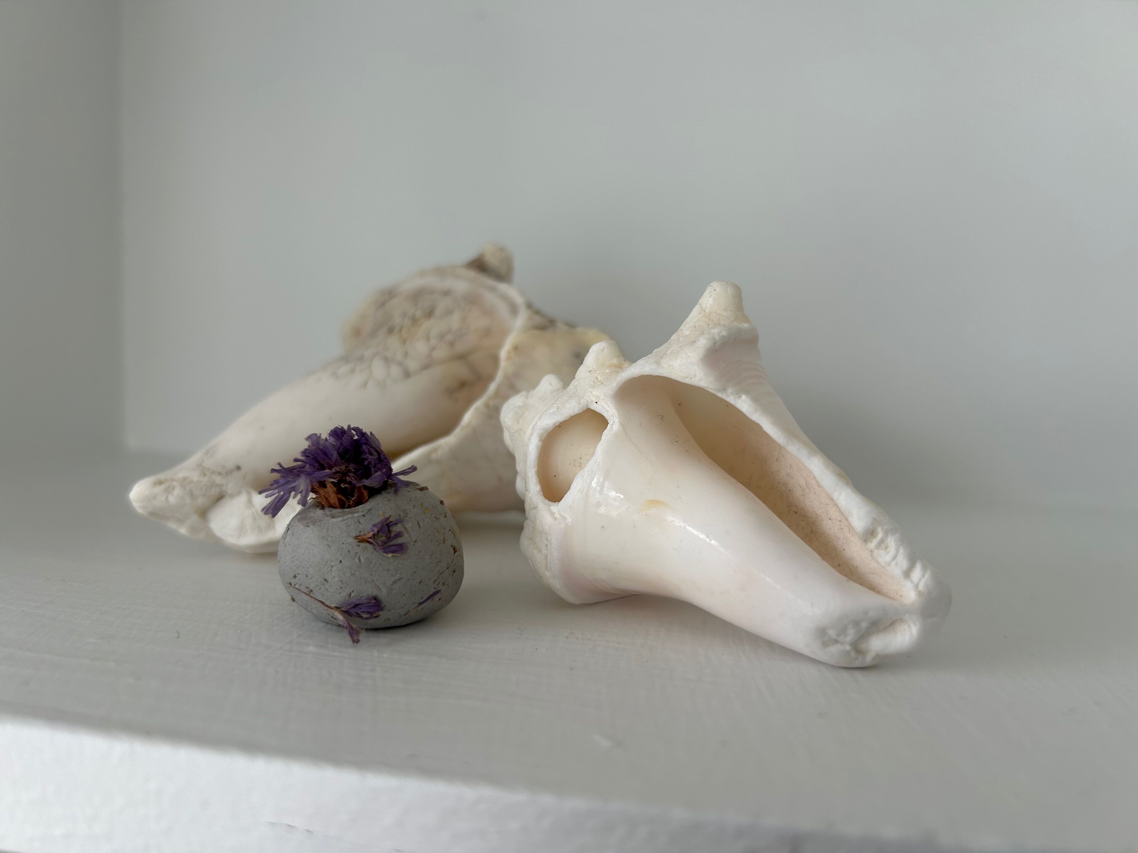 Un petit vase en céramique orné de fleurs violettes, posé sur une surface blanche.